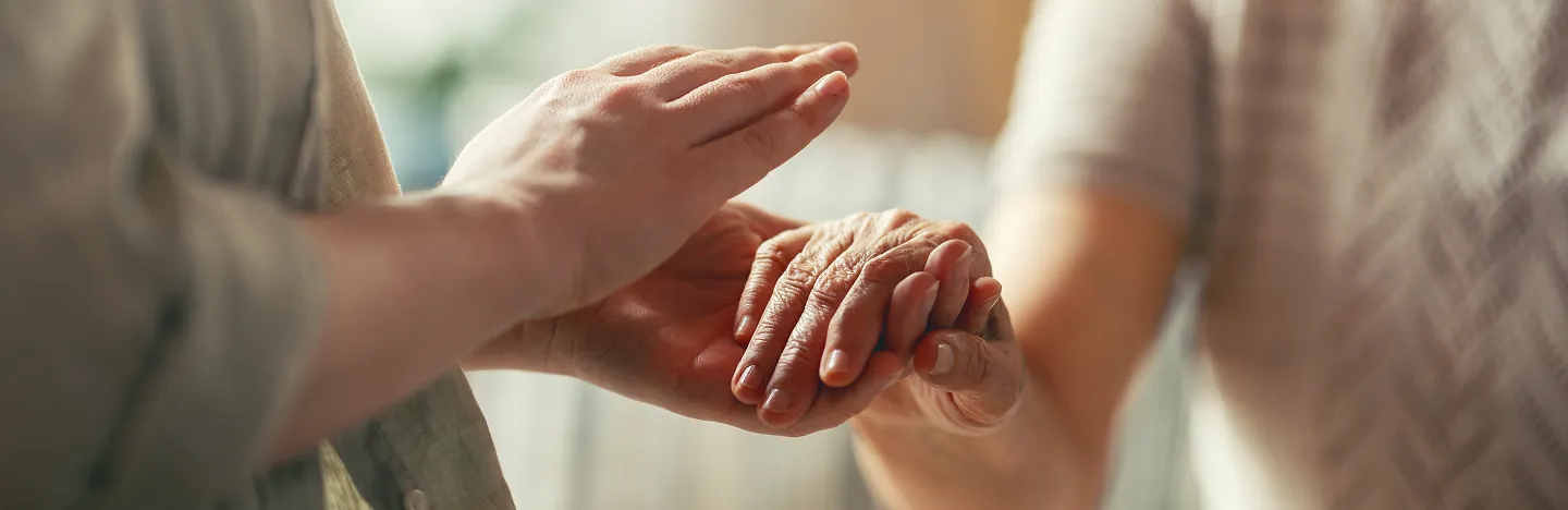 Caregiver holding hands with senior client